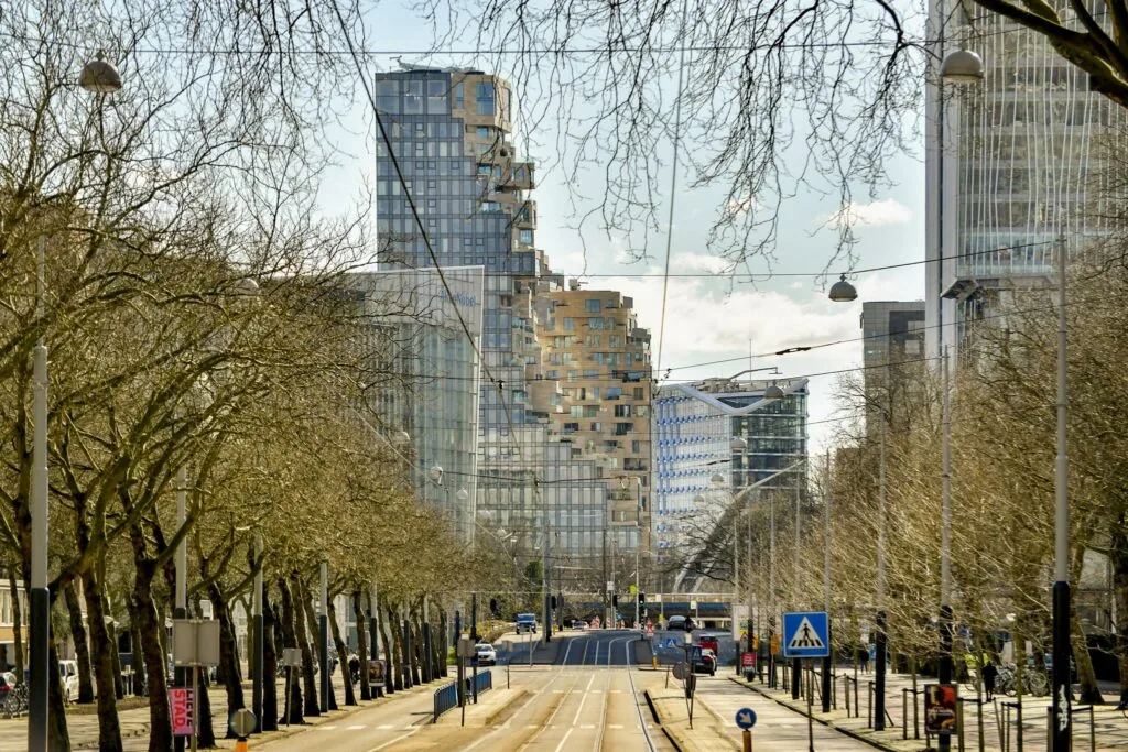Uitzicht op de Cornelis Dopperkade in Amsterdam met moderne hoogbouw en kale bomen langs de trambaan.